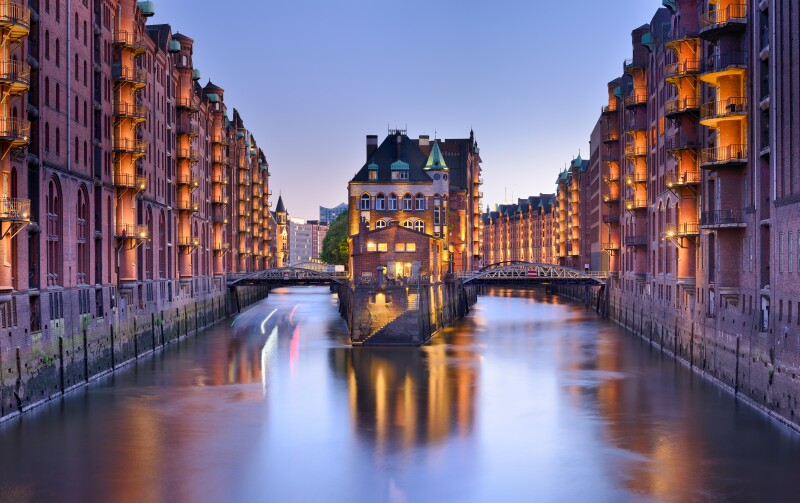 Tall, residential, 19th-century style buildings flanking a river in Speicherstadt, Germany