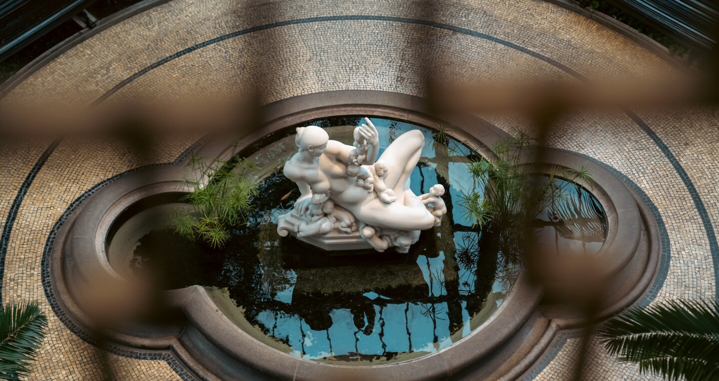 A marble sculpture of women and children set in a body of water at the Glyptoteket museum in Copenhagen, Denmark