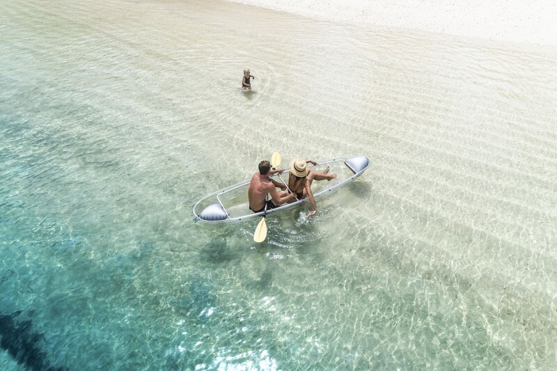 Overhead view of two people in small paddleboat in shallow water