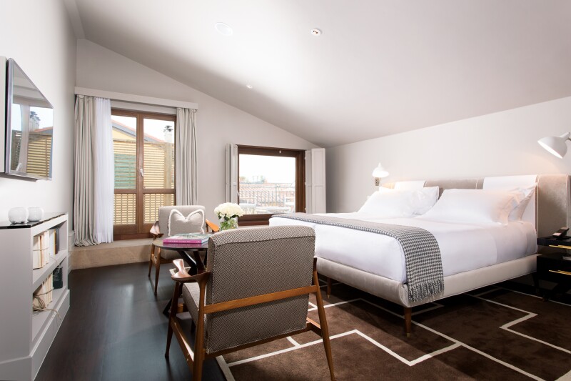 Brown and white guest room with sleek, modern furnishings and slanted ceiling