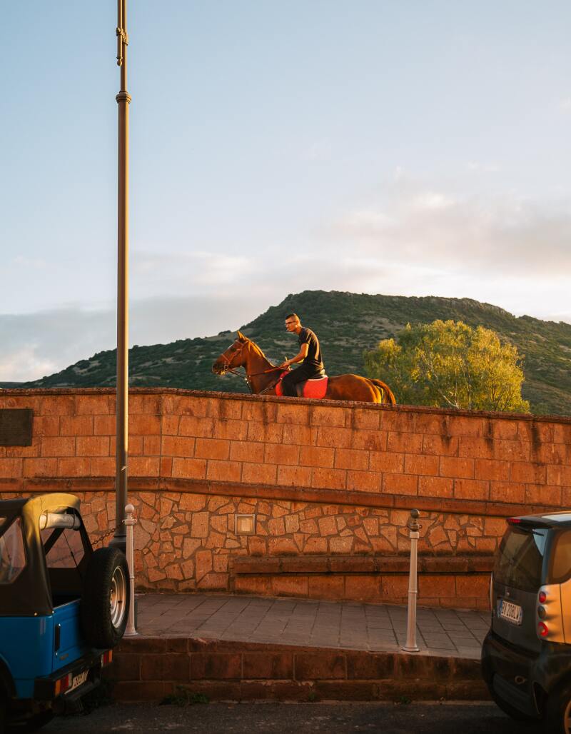 A man travels through a city center on horseback.