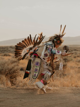 A person in traditional indigenous garb dances at the Numaga Powwow