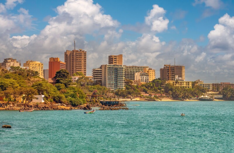 Several tall buildings line the coastline in Dakar, Senegal, with turquoise-blue water all around