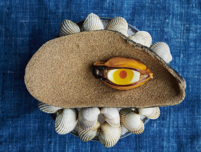 A blue mussel and quail egg served on a large shell