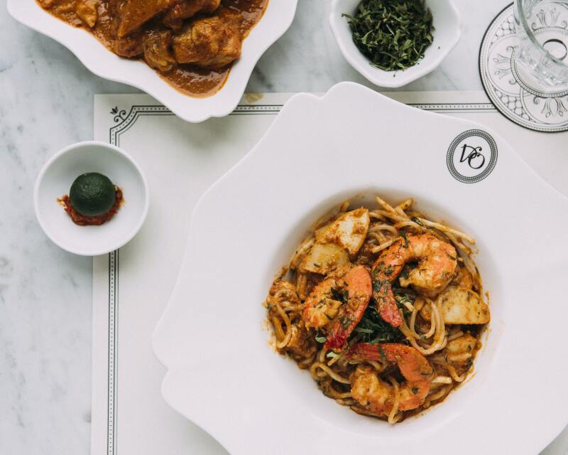 Overhead view of fancy white bowl of laksa with several shrimp at National Kitchen