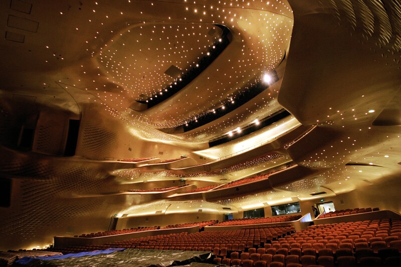 Interior of main auditorium of the Guangzhou Opera House, with copper-colored gypsum-paneled ceiling holding thousands of tiny lights
