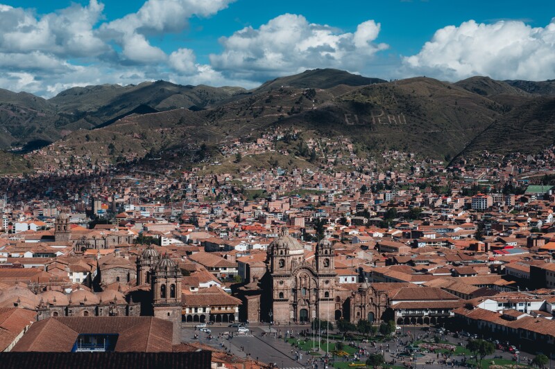 Aerial view of main square in Cusco, with large church at one end and mountains in distance