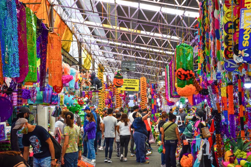 People walking among hanging Halloween decorations in indoor market