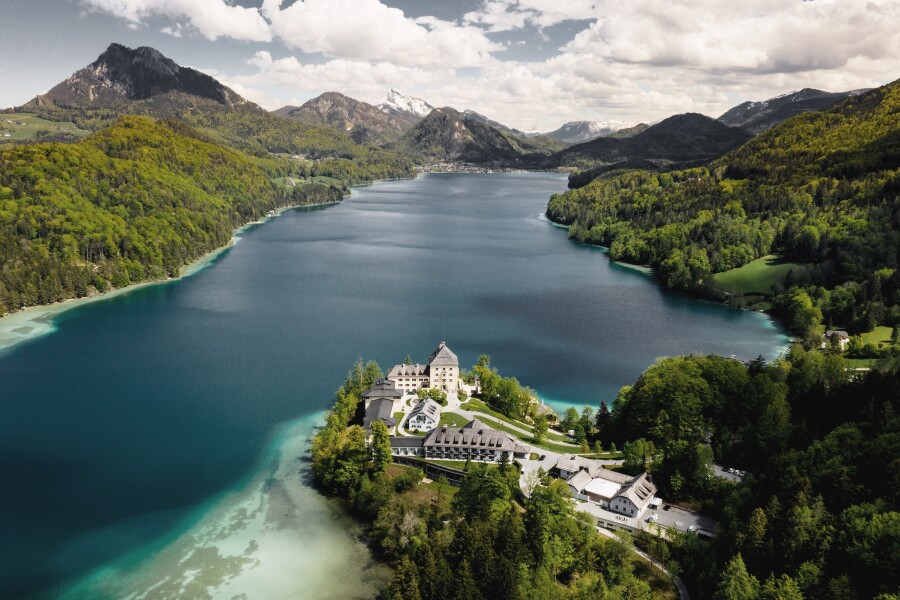 Aerial view of Rosewood Schloss Fuschl, located in a restored castle on Lake Fuschl surrounded by tree-covered hills