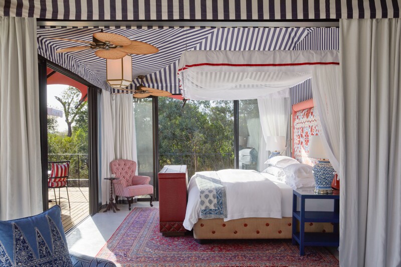 A guest room at Masiya's Camp with black-and-white–striped ceiling covers and a large private veranda