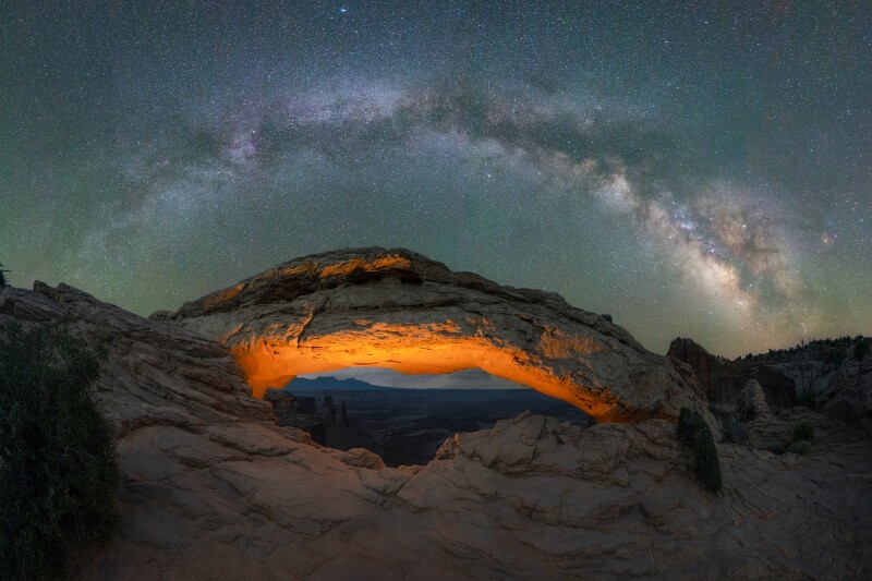 Milky Way Galaxy panorama over a lit Mesa Arch in Canyonlands National Park, Utah