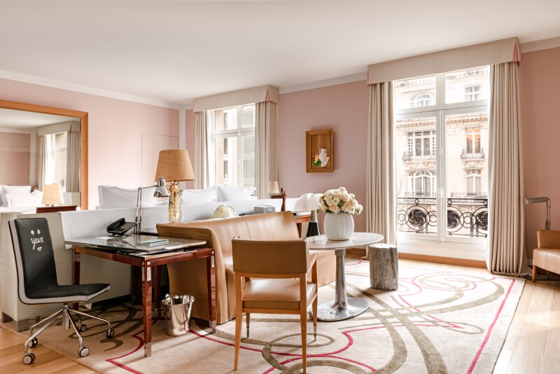 Interior of a Gallery Suite, with large windows, pale pink walls, modern furniture, and patterned carpet on wood floor