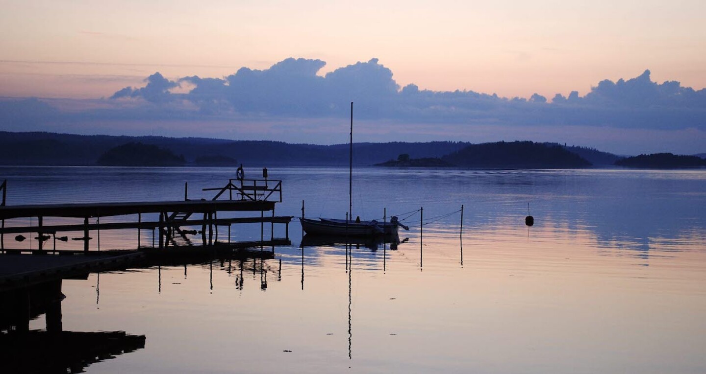 A dock on a lake. Large clouds are in the sky.