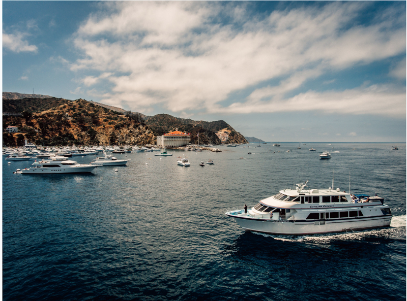 White ferry in foreground approaching harbor on island