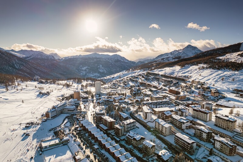 Aerial view of the Italian mountain village of Sestriere blanketed by snow and surrounded by mountain peaks