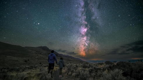 Two people in nature with the night sky above the Warner Valley Overlook in Oregon