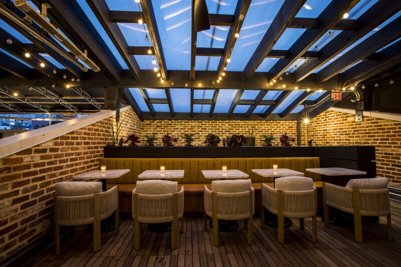 The patio at Death & Co D.C. at night, with brick walls