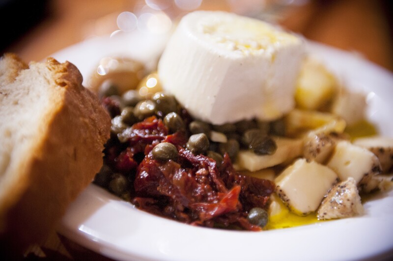 Plate of local food from Malta, including ġbejniet, olive oil, capers, and tomatoes.