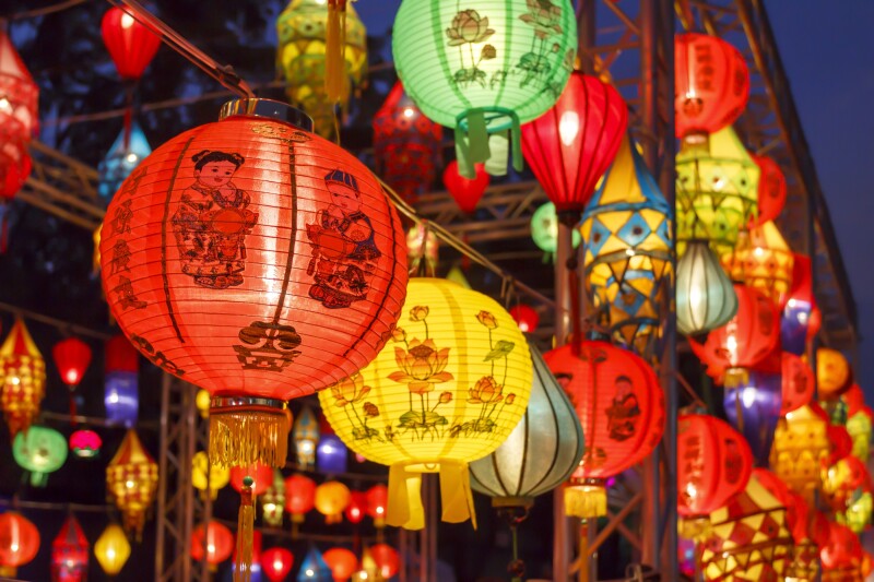 Rows of hanging lit Chinese lanterns, mostly red or yellow globes