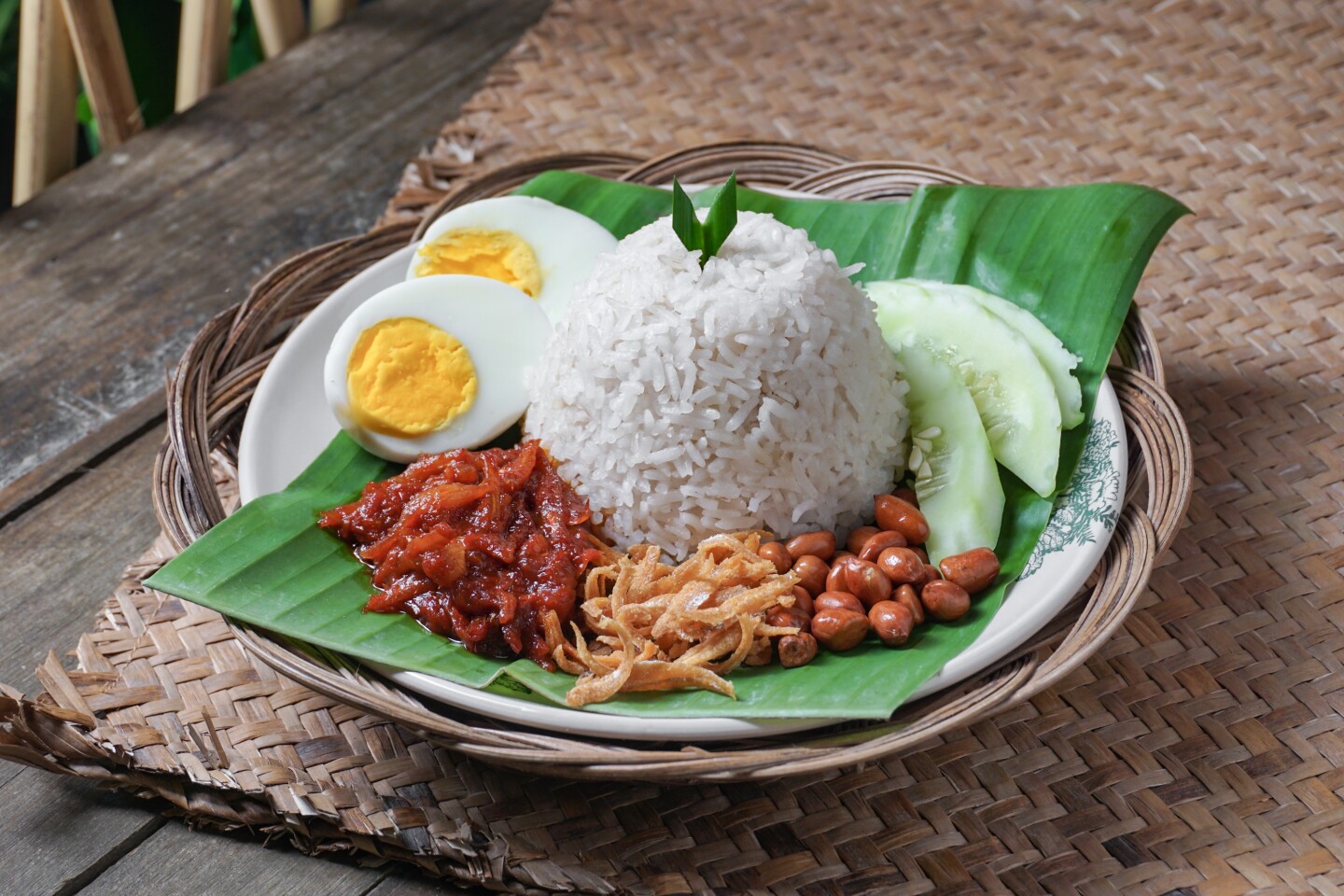 Asian food Nasi Lemak is a rice dish infused with coconut milk. Served with sambal, fried anchovies, fried peanut, boiled eggs, and fresh cucumber.