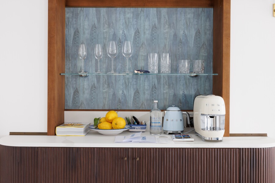 The minibar at Borgo Santandrea on Italy's Amalfi Coast features a blue feathered backdrop and ribbed wooden cabinetry.