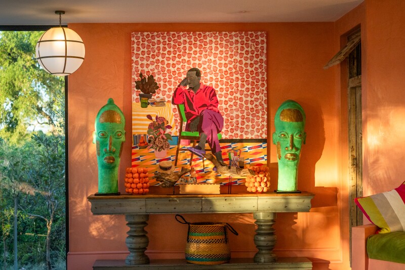 A painting of a man in a chair hangs on an orange wall at Masiya's Camp