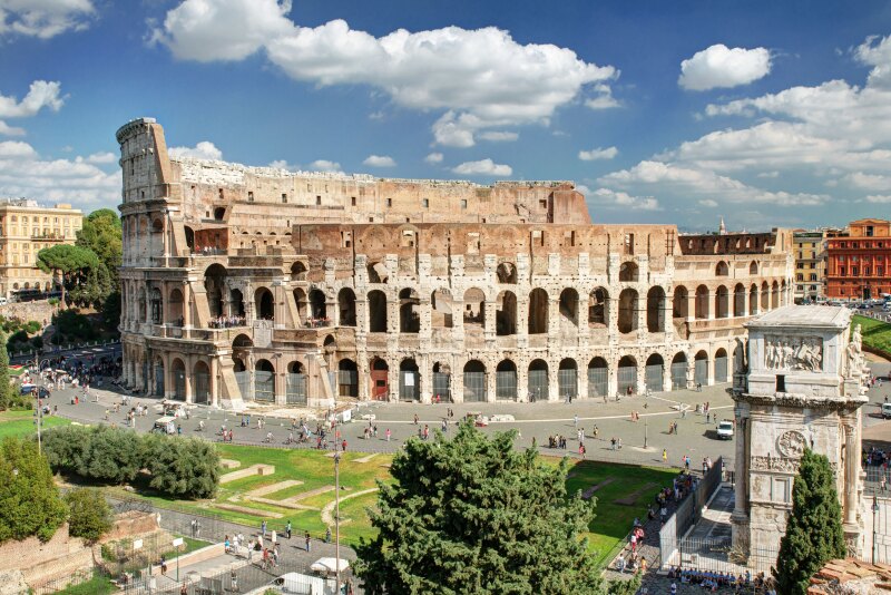 Ancient colosseum set in an urban area with people walking around