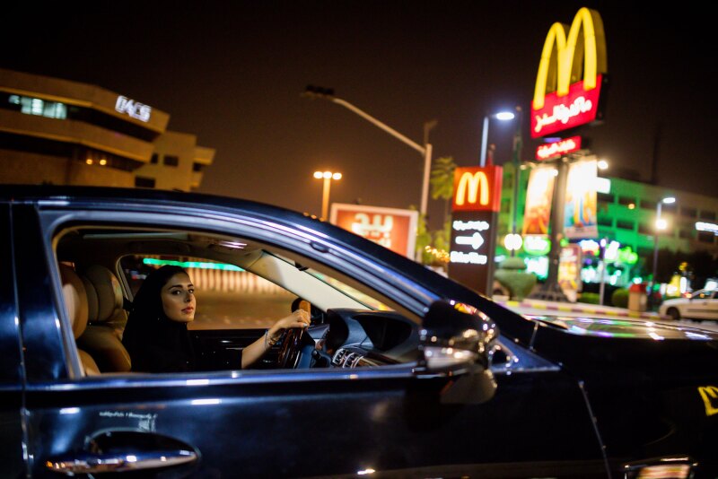 Photo of a woman driver in hijab near a McDonald's drive through.