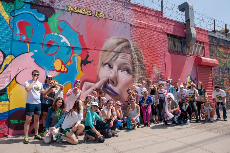 Group of people impersonating a mural of a person sticking their finger up their nostril