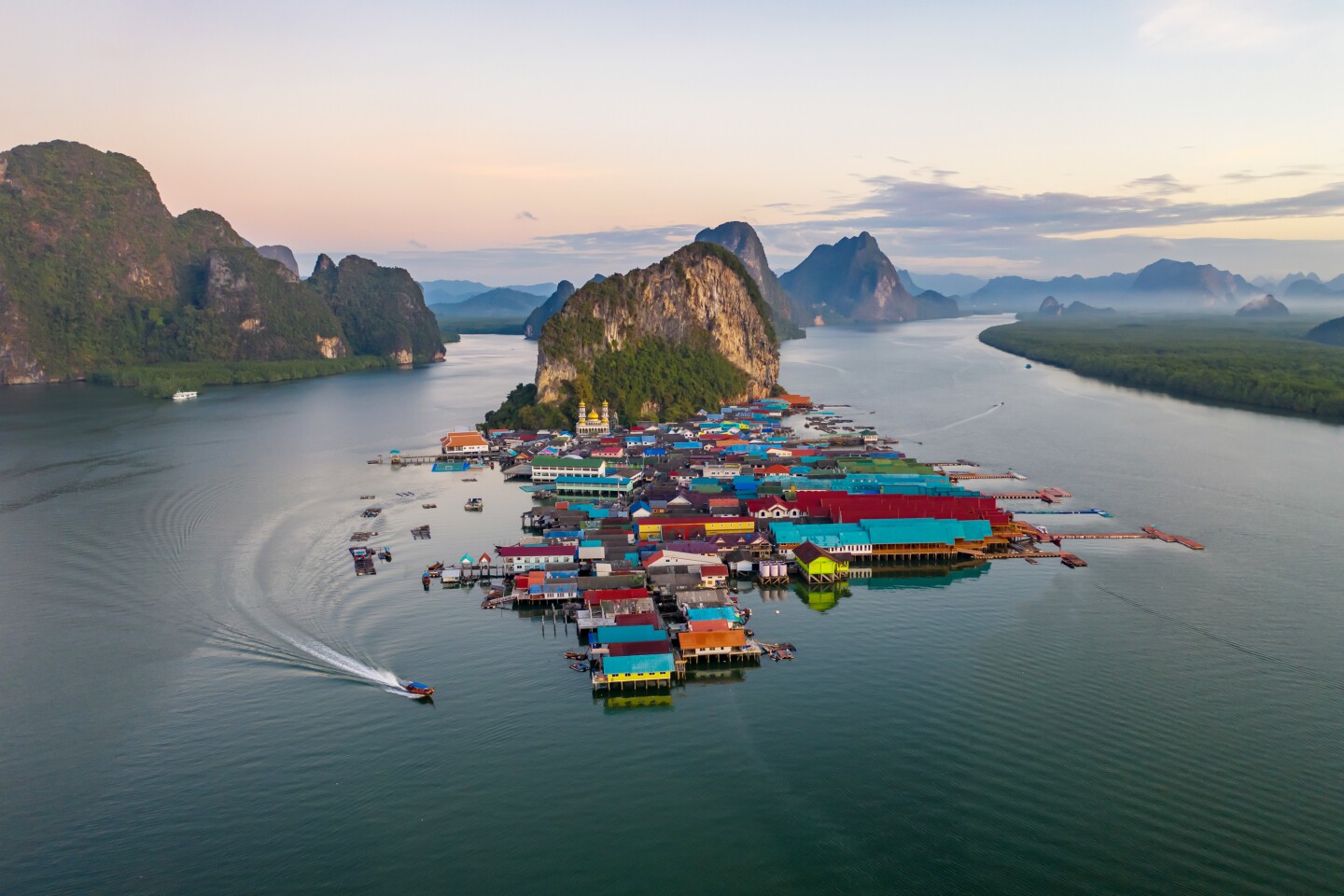 Aerial panorama view over colorful (mostly turquoise and red) Ko Panyi floating village, with rugged hills in distance