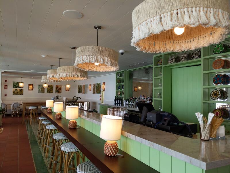 A bar with green walls and fringed pendant lamps at the Sofitel Legend hotel