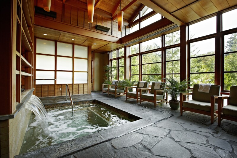 The indoor hot tub area of the Salish Lodge and Spa in Snoqualmie, with wall of windows behind six empty armchairs