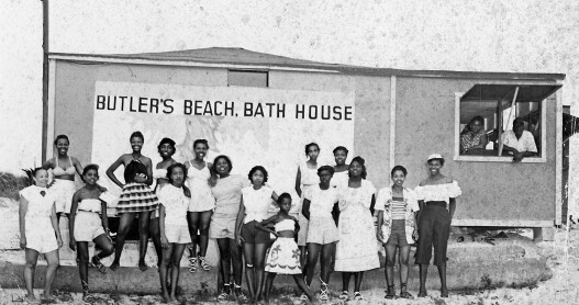 a black and white historic photo of a group of black people posing on the beach on historic Butler Beach Florida , part of the St. Johns County Black Heritage Trail