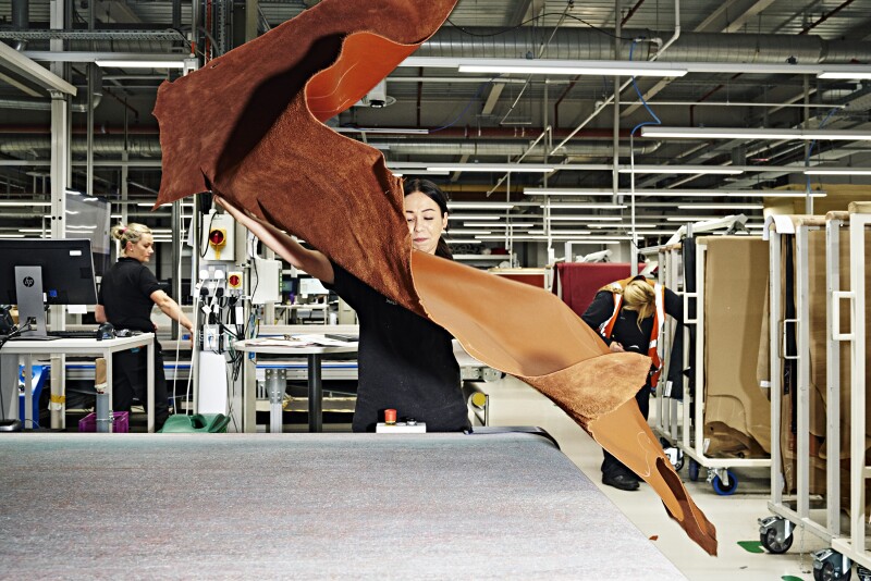 A worker prepares to cut a piece of leather for an interior.