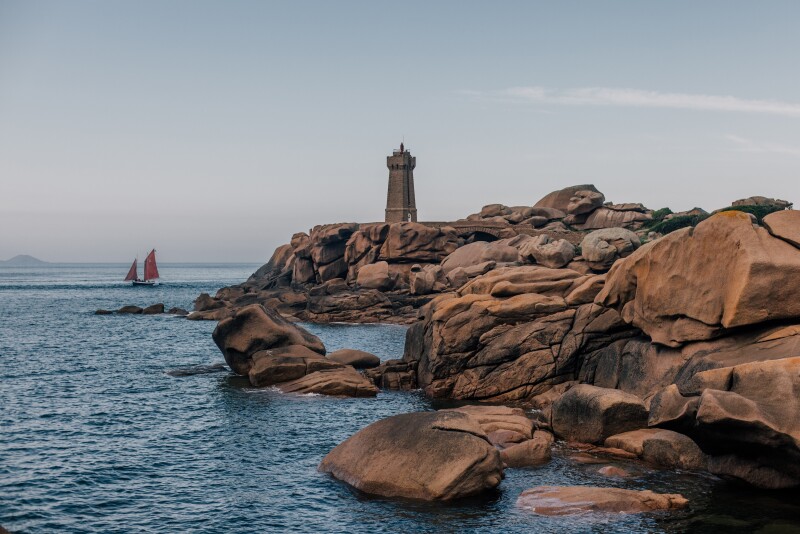 Coastside large granite rocks with small lighthouse in distance