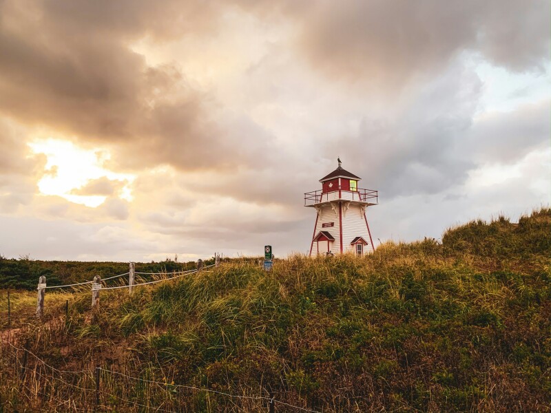 Red and white lighthouse on a grassy field