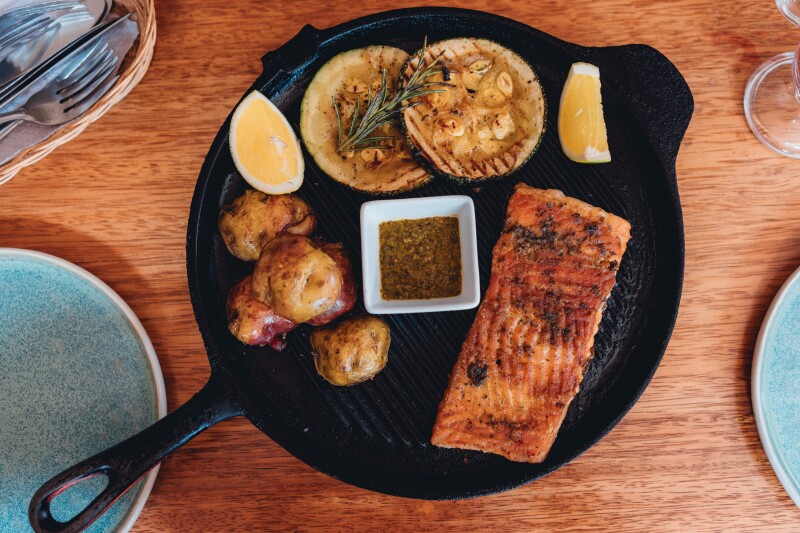 Overhead view of salmon and potatoes on a black skillet at Ama restaurant in Urubamba