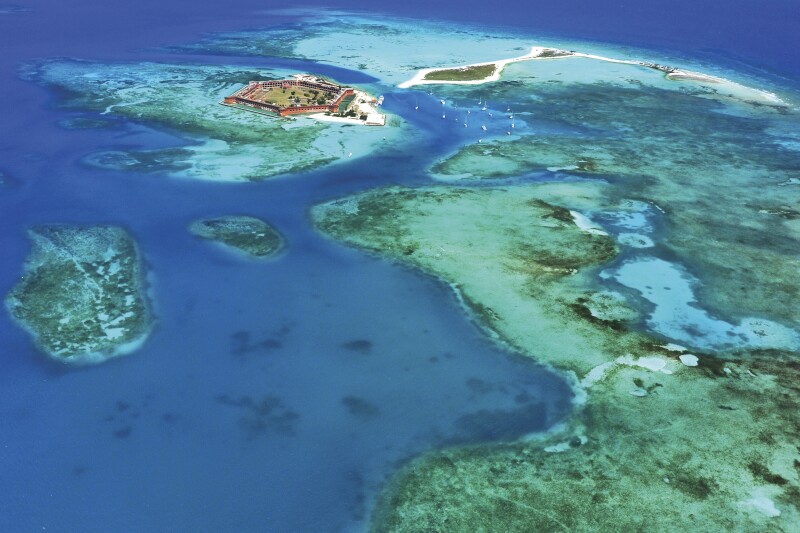 Aerial shot of a walled fort and small islands, with blue and turquoise water