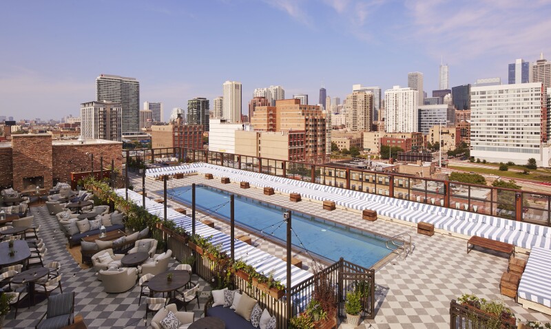Overhead view of large rectangular rooftop pool surrounded by geometric patterned tiles, with restaurant on one side