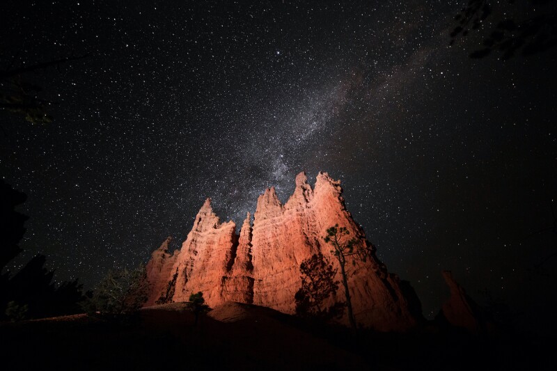 Red rock hoodoo formations under a dark night sky filled with stars