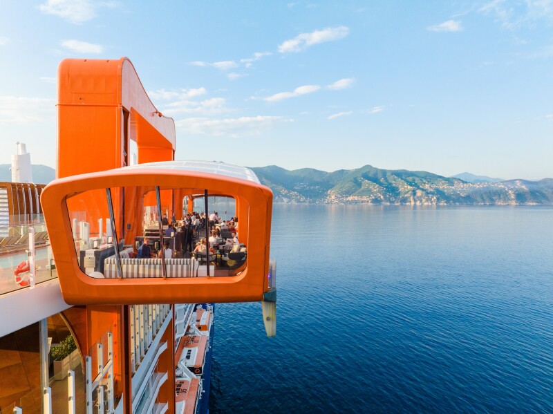 A rendering of the orange "magic carpet" movable dining concept that attaches to the side of the forthcoming 'Celebrity Xcel' cruise ship and can move up and down the ship