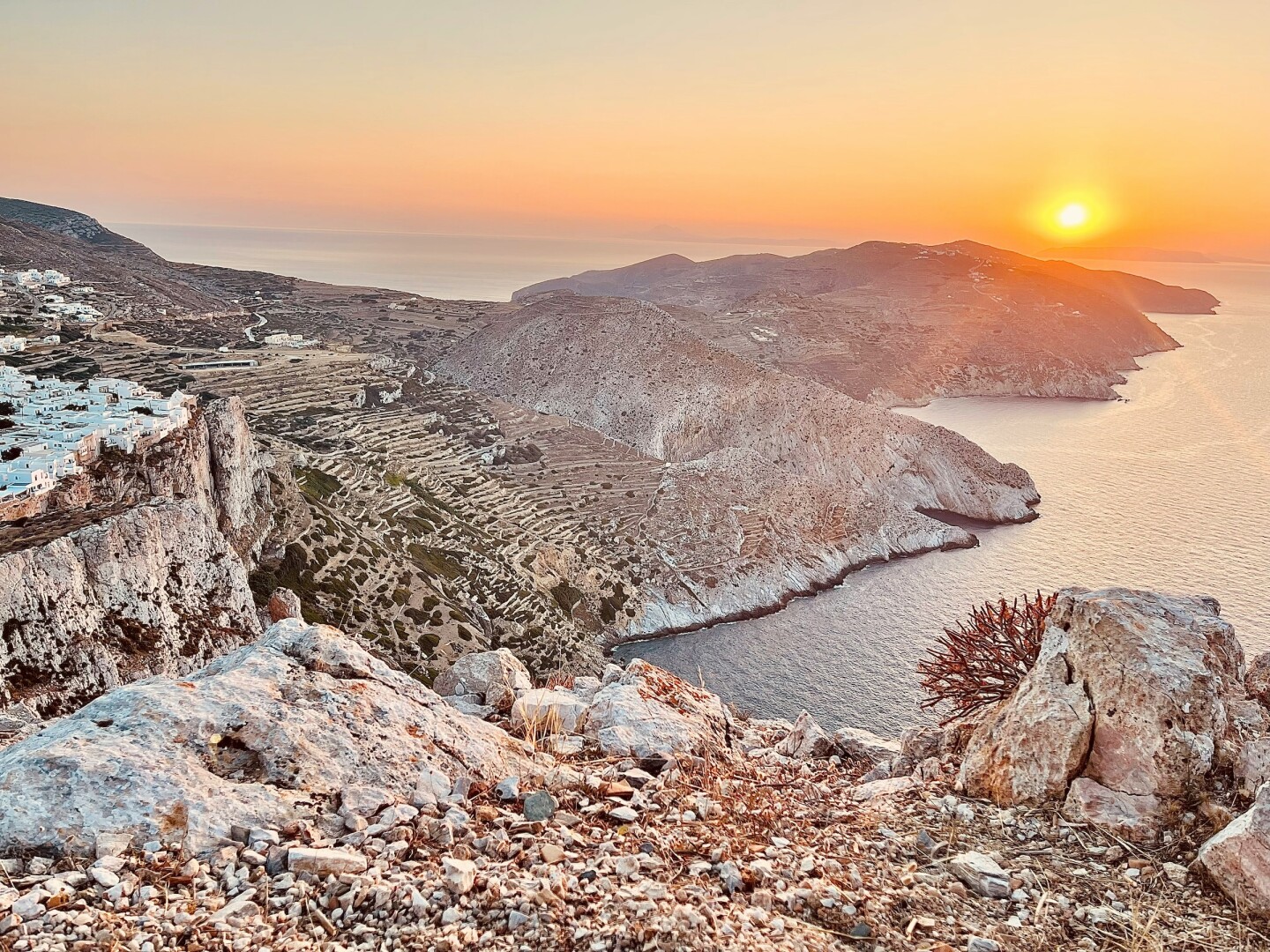 Sunset over an island with stone mountains and terraced hillsides 