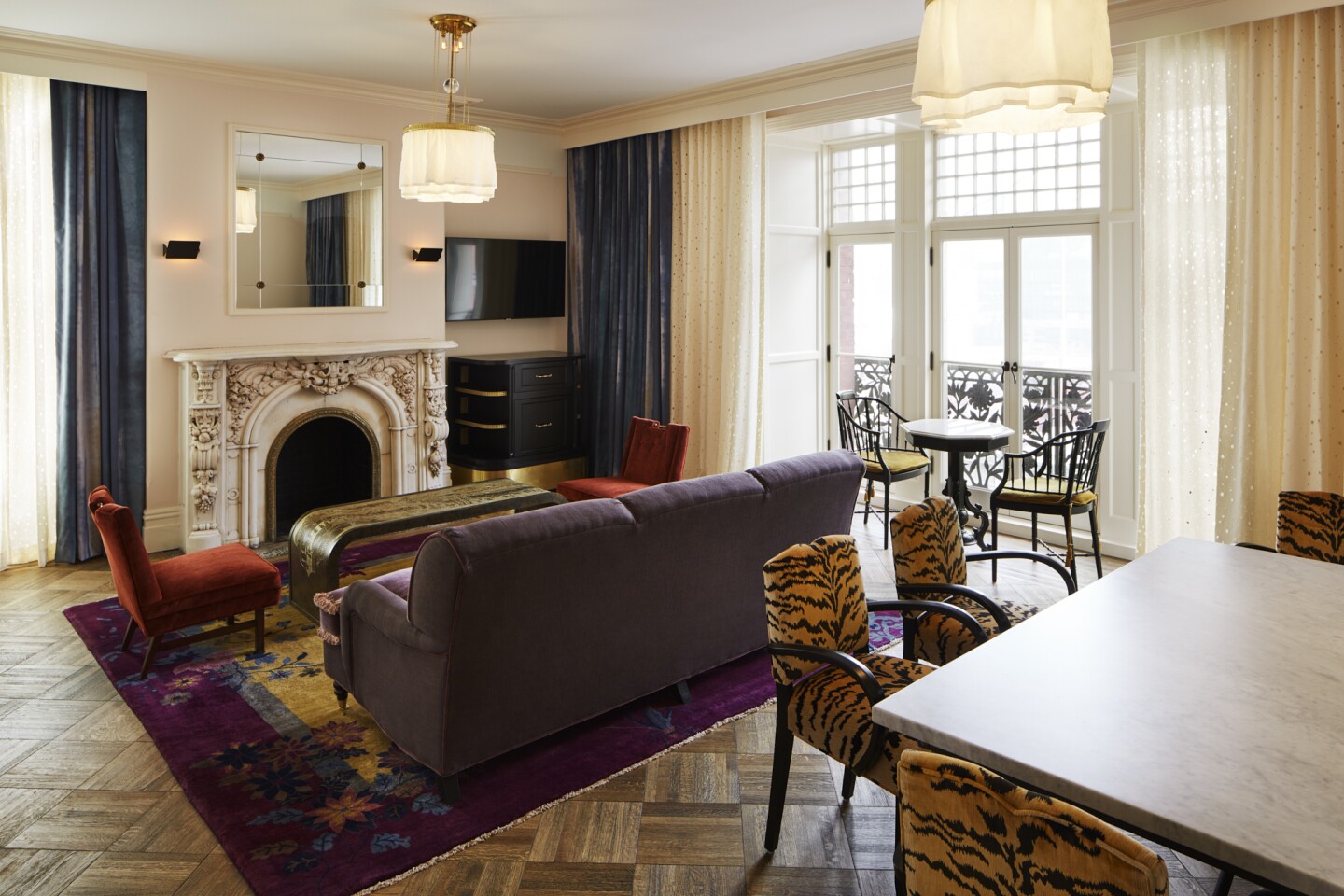 A guest room at the Hotel Chelsea in NYC with a fireplace and floor-length curtains.