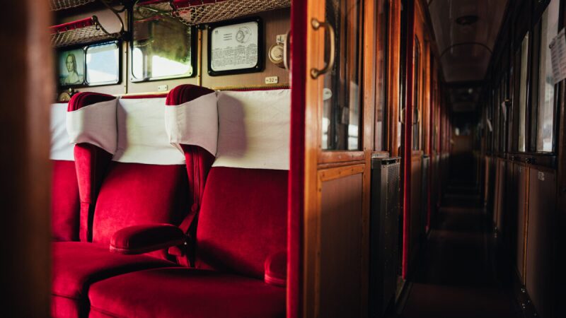 interior of Italy's Dante Train with red seats and wooden sliding doors and panels