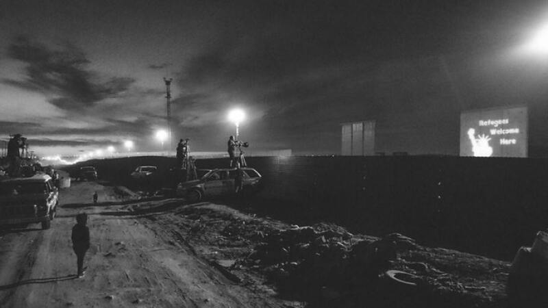 The Overpass Light Brigade projects messages of hope on the border wall prototypes in San Diego.