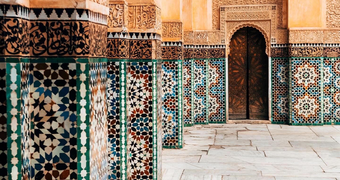 Geometric tiles line a walkway leading to an inset door