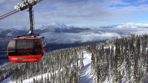 View of a gondola moving above a ski area with a mountainous backdrop in Whistler.