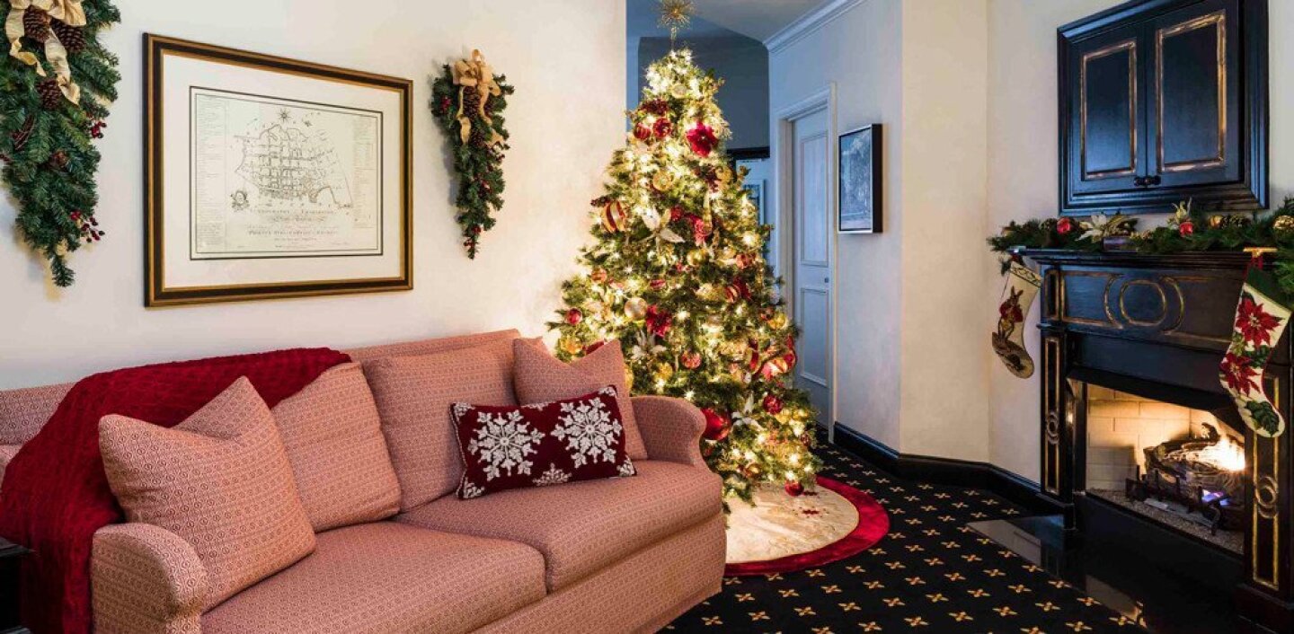 Red sofa and decorated Christmas tree in front of a fireplace