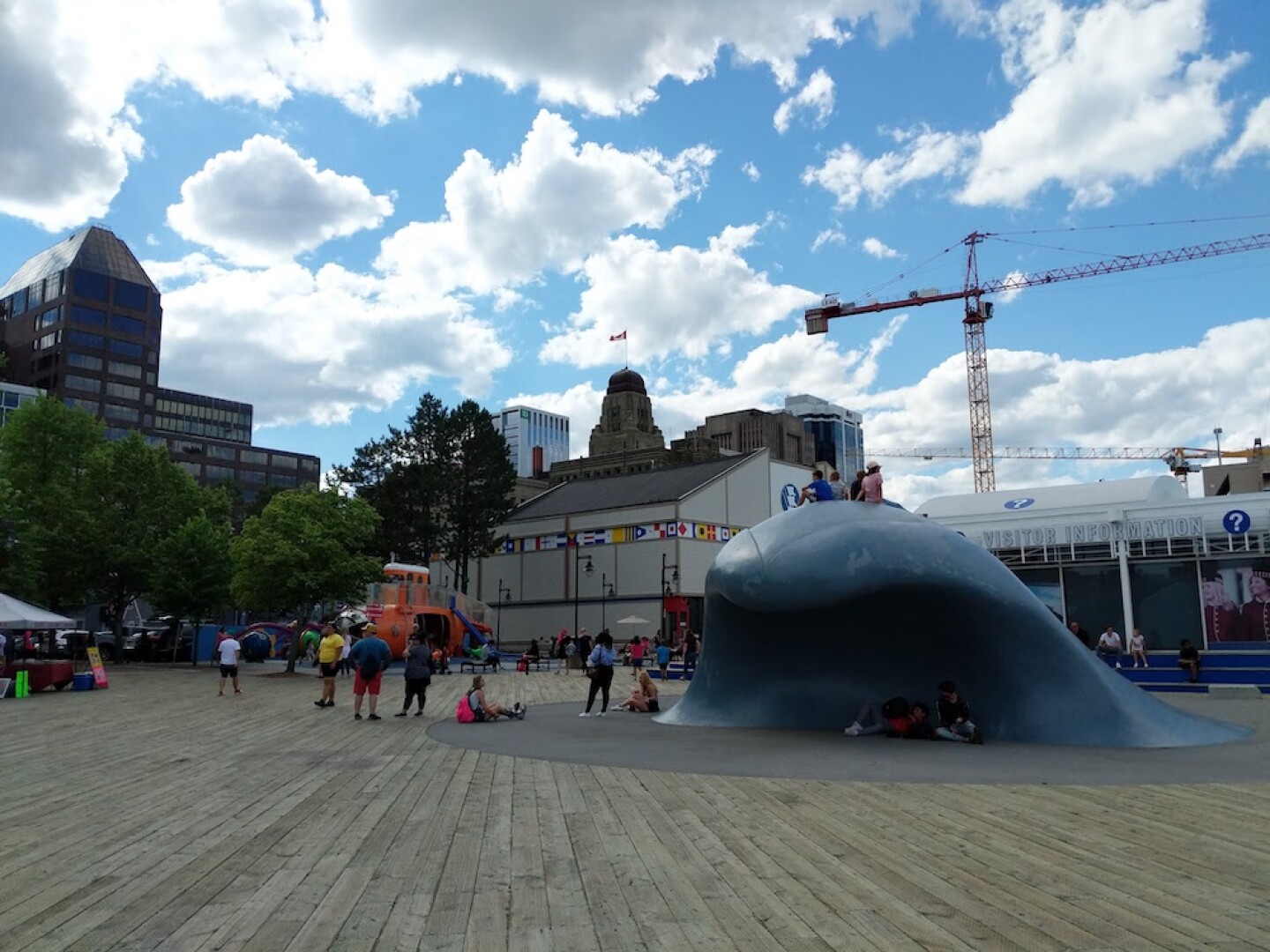 People sitting on top of a wave sculpture on a wooded boardwalk.