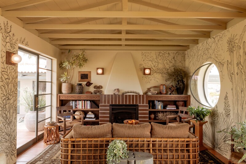 A beige-toned living area in Hotel Wren, with a sofa, a fireplace, and a sliding glass door leading to outside